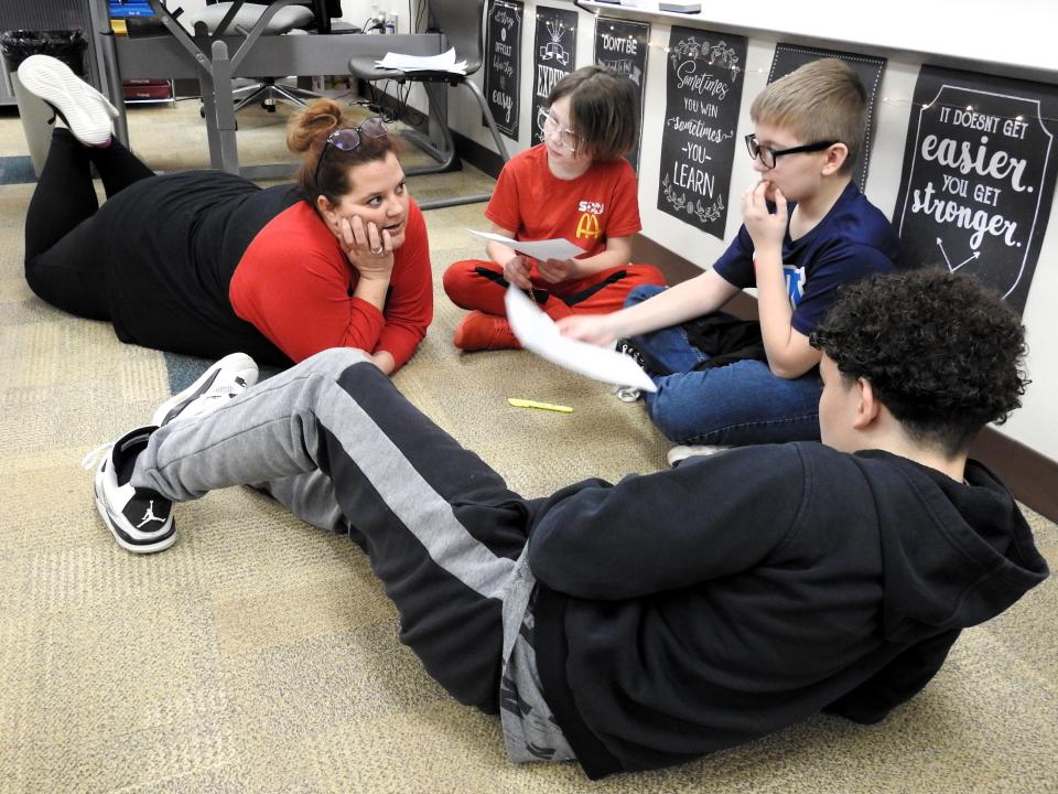 Intervention specialist Samantha Rotruck at Coshocton Elementary School works with a small group of sixth grade students reading an article about sled dogs versus snow mobiles related to a unit on the Iditarod Sled Dog Race. She used AI to scale the article to different reading levels and the students were grouped based on those reading levels.