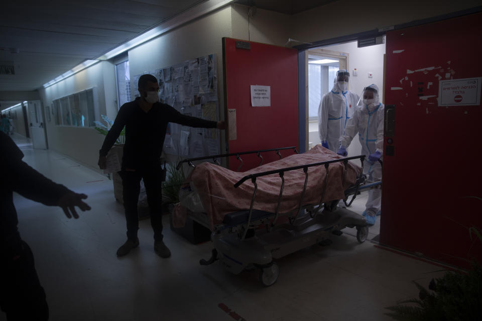 Medical personnel wearing protective equipment move the body of a man who died from COVID-19, in the intensive care ward for coronavirus patients at Shaare Zedek Medical Center, in Jerusalem, Monday, Nov. 23, 2020. (AP Photo/Oded Balilty)