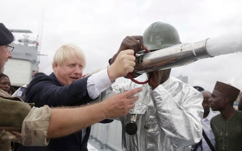 British Foreign Secretary Boris Johnson, centre, uses a water cannon onboard a Nigeria Naval warship during a visit to the Nigeria Navy at the Naval dockyard in Lagos, Nigeria - Credit: Sunday Alamba/AP