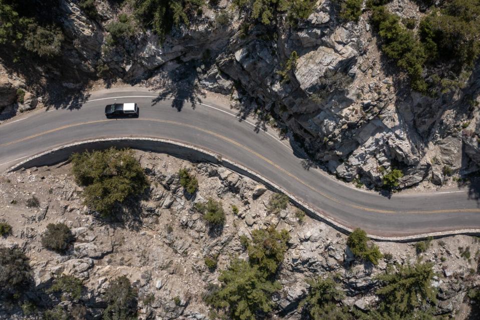 An aerial view of a road snaking through a mountain wilderness.