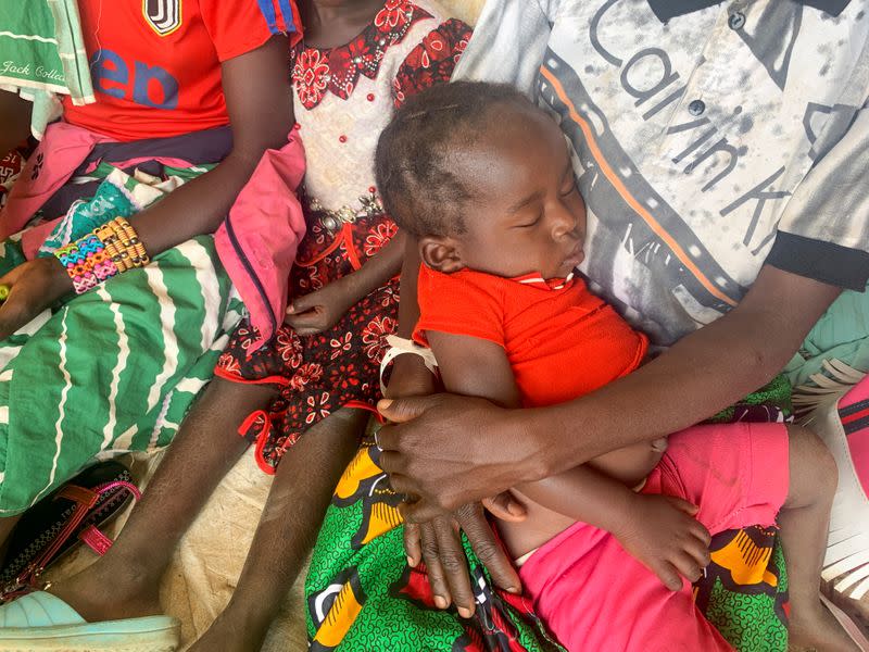A woman who fled the violent rebellion in Central African Republic (CAR) holds her sleeping child as they wait for their identification process in the border town of Garoua Boulai