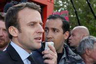 Emmanuel Macron, head of the political movement En Marche !, or Onwards !, and candidate for the 2017 French presidential election, flanked by Alexandre Benalla (R), head of security, uses a megaphone to talk to Whirlpool employees in front of the company plant in Amiens, France, April 26, 2017. Picture taken April 26, 2017. REUTERS/Pascal Rossignol