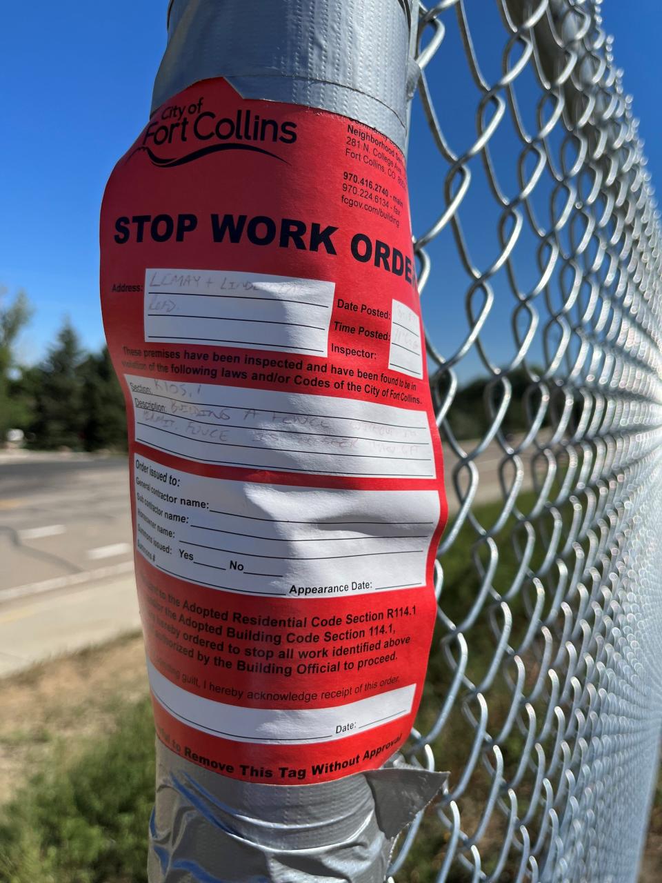 A stop work order is posted on a chain-link fence along North Lemay Avenue where it intersects with the Larimer-Weld Canal.