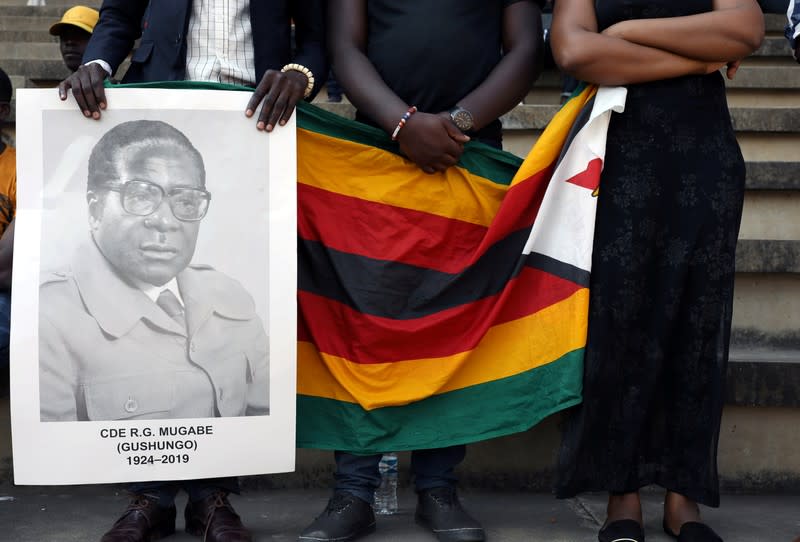 FILE PHOTO: Mourners hold a poster during the state funeral of Zimbabwe's longtime ruler Robert Mugabe at a national sports stadium in Harare