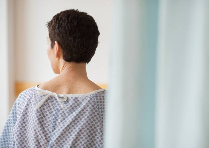 Person in a hospital gown looking out a window, suggesting contemplation or recovery