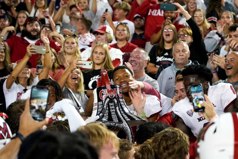 Miami RedHawks hoist the Victory Bell in the air after winning their football game against the rival Cincinnati Bearcats after the NCAA football game between the Cincinnati Bearcats and the Miami RedHawks at Nippert Stadium in Cincinnati on Saturday, Sept. 16, 2023. Miami (Oh) won 31-24.