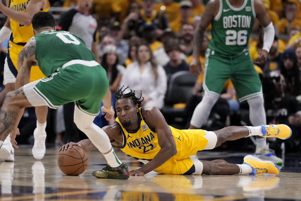 Indiana Pacers forward Aaron Nesmith (23) dives for a loose ball in front of Boston Celtics forward Jayson Tatum (0) during the second half of Game 3 of the NBA Eastern Conference basketball finals, Saturday, May 25, 2024, in Indianapolis. (AP Photo/Michael Conroy)