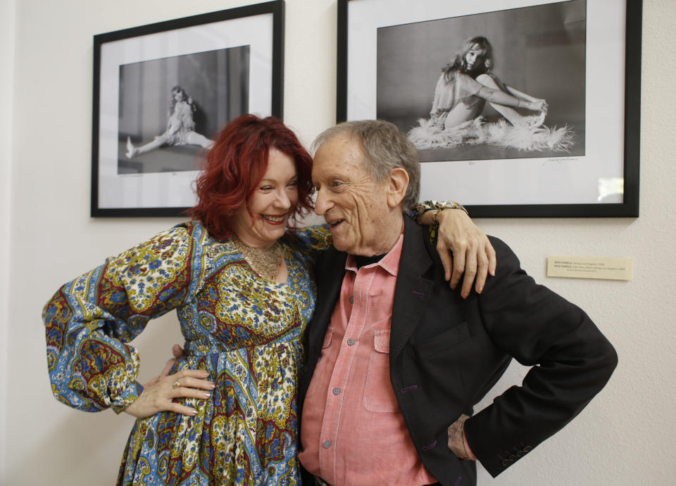 In this photo taken Saturday, April 13, 2013 former Rolling Stone photographer Baron Wolman, right, embraces Pamela Des Barres, left, the subject in both photographs on the wall behind during the opening of Wolman's photo exhibit "The Groupies" at Markham Vineyards in St. Helena, Calif. More than 75 wineries have art on display all year long. (AP Photo/Eric Risberg)