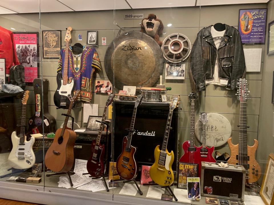 A curated display of garments and instruments at The Allman Brothers Band Museum.