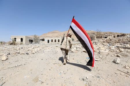 FILE PHOTO: A pro-government army soldier carries Yemen's national flag as he walks at the strategic Fardhat Nahm military camp, around 60km (40 miles) from Yemen's capital Sanaa, February 11, 2016. REUTERS/Ali Owidha/File Photo