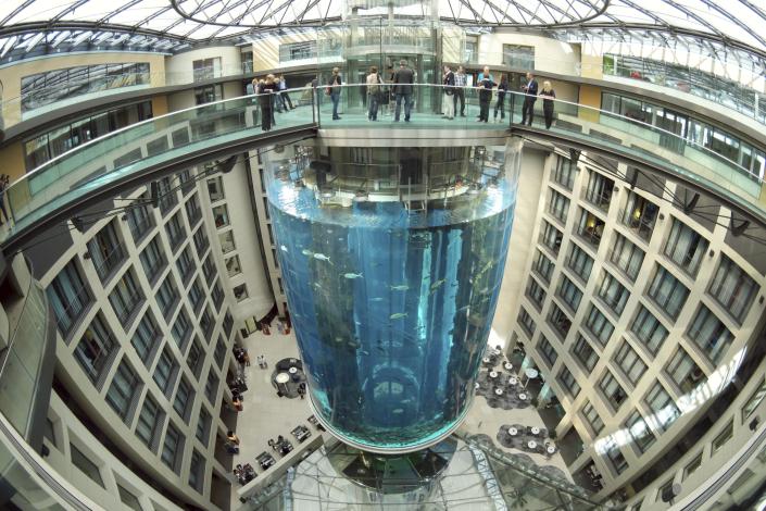 People gather on the top of the AquaDom aquarium at the Sea Life tourist attraction in Berlin, July 27, 2015. The aquarium is bursts on Friday, Dec. 16, 2022. Operators say the aquarium has the biggest cylindrical tank in the world. It contained 1,500 tropical fish before the incident. (Joerg Carstensen via DPA)