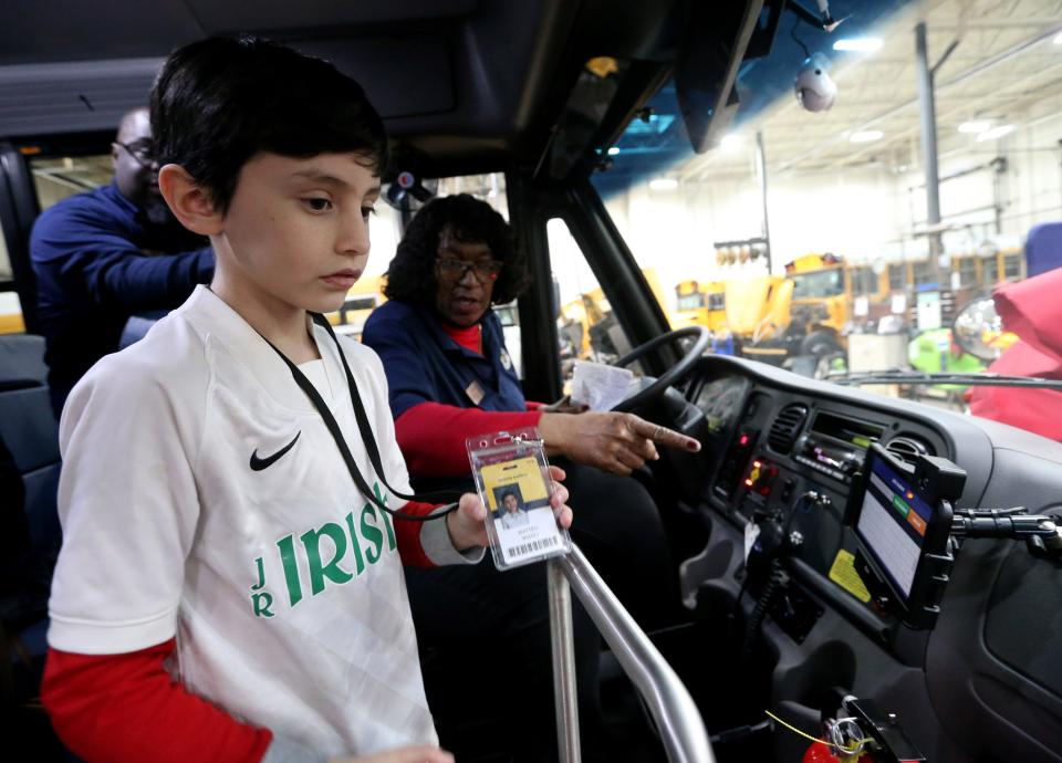 Matteo Vasoli, a second-grade student at Kennedy, shows his badge as Sandra Jones, bus driver and trainer, shows him where to scan it into a new tracking system in one of the two new all-electric school buses Friday, Jan. 27, 2023, at the South Bend school district’s bus facility on Bendix Drive in South Bend.