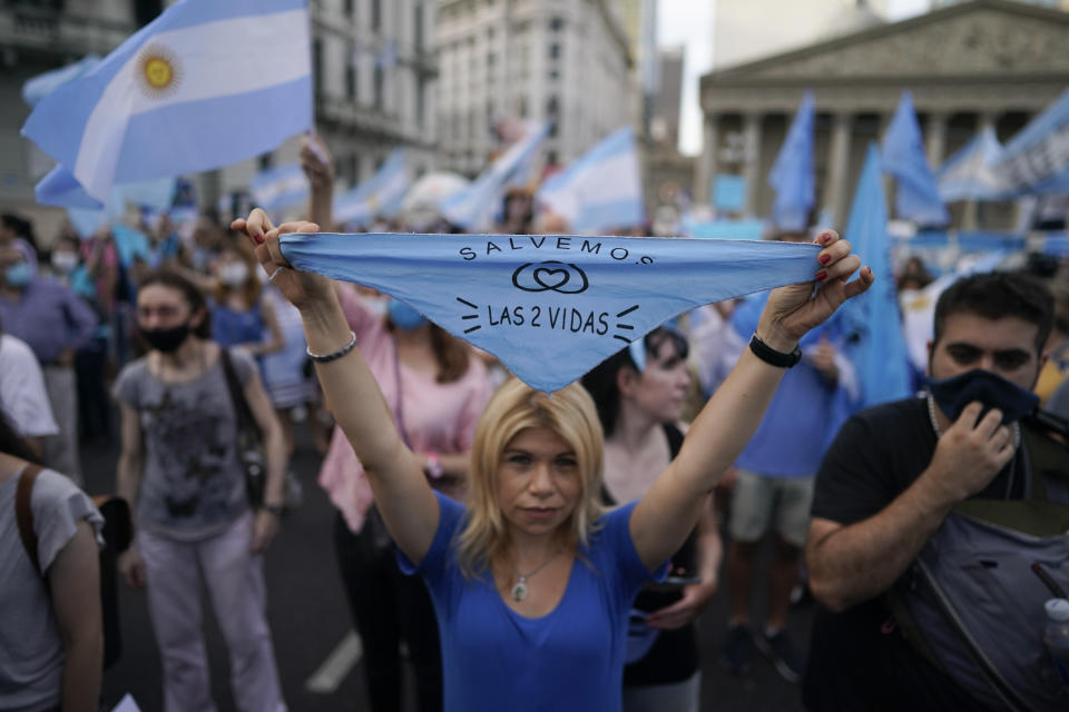 An activist against abortion holds a handkerchief with text in Spanish that reads " Save both lives," as she protests against the decriminalization of abortion, one day before lawmakers will debate its legalization, at Plaza de Mayo in Buenos Aires, Argentina, Monday, Dec. 28, 2020. (AP Photo/Victor R. Caivano)