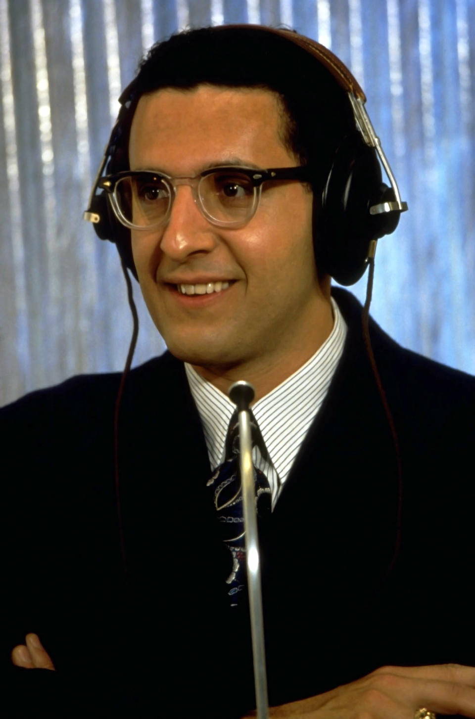 Turturro wearing a suit and headphones a contestant in the quiz show