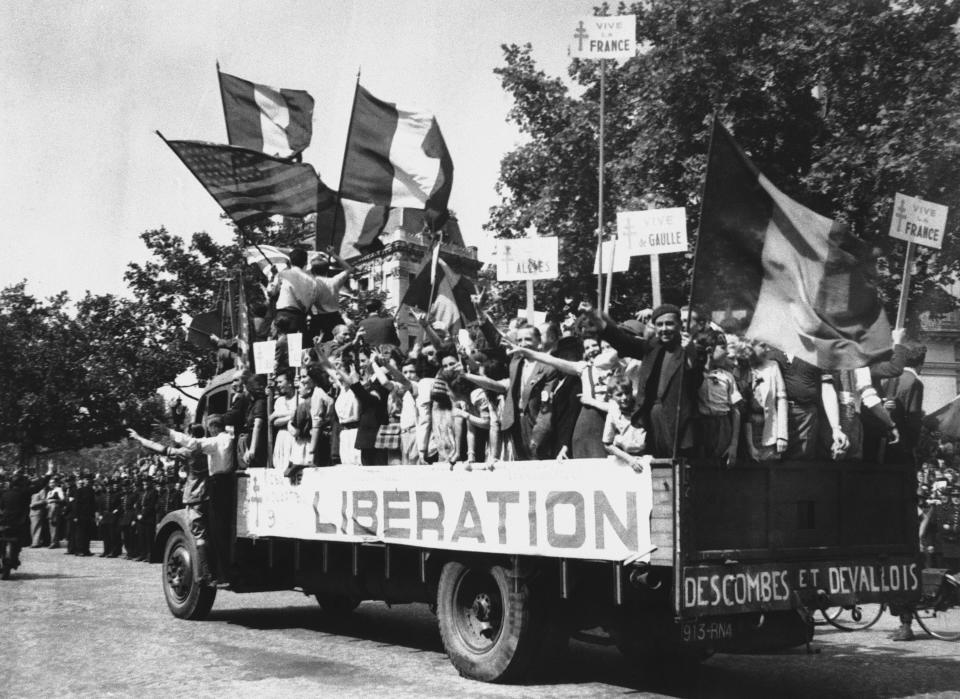 Un grupo de ciudadanos recorre las calles de París montados en un camión portando banderas de Francia y de Estados Unidos y pancartas que celebran la liberación el 28 de agosto de 1944. (Foto: Peter Carroll / AP).