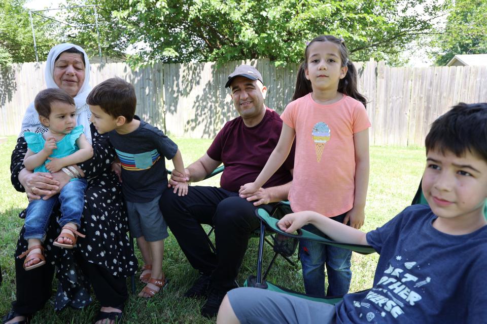 Tamim Bedar, who fled Afghanistan during the U.S. evacuation in 2021, sits with his children and a relative outside his home in Louisville, Kentucky.