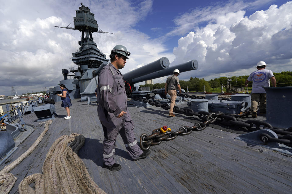 Workers walk across the deck of the USS Texas Tuesday, Aug. 30, 2022, in La Porte, Texas. The USS Texas, which was commissioned in 1914 and served in both World War I and World War II, is scheduled to be towed down the Houston Ship Channel Wednesday to a dry dock in Galveston where it will undergo an extensive $35 million repair. (AP Photo/David J. Phillip)