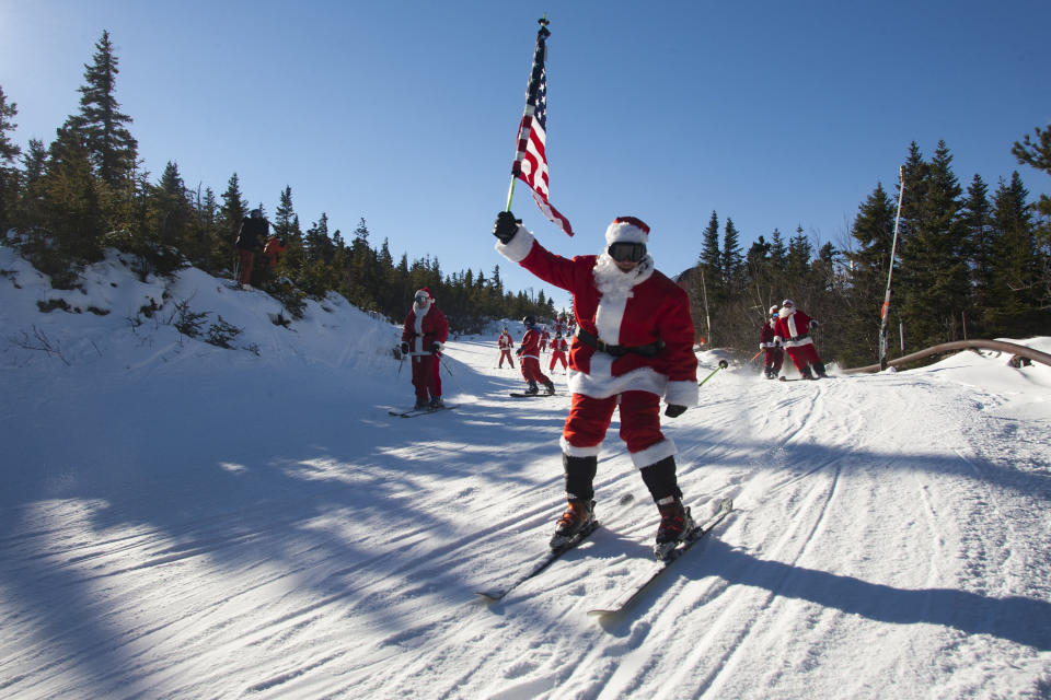 A skier dressed like Santa heads down the slopes with an American flag in the air.&nbsp;