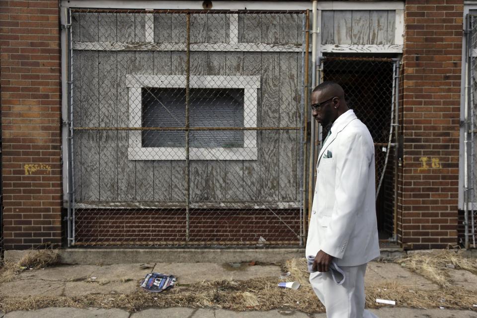 In this Thursday, Jan. 16, 2014 photo, Melvin White, founder of the Beloved Streets of America project, walks past a boarded up building during a tour of Dr. Martin Luther King Jr. Drive in St. Louis. The nonprofit is working to revitalize a downtrodden six-mile stretch of the drive named for the slain civil rights leader, marked by vacant lots, crumbling buildings and a preponderance of liquor stores, pawn shops and check-cashing businesses. Project leaders hope revitalize MLK's streets that have fallen into disrepair in cities around the country. (AP Photo/Jeff Roberson)