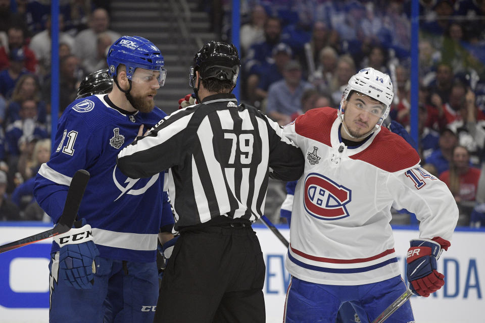 linesman Kiel Murchison (79) separates Tampa Bay Lightning defenseman Erik Cernak (81) and Montreal Canadiens center Nick Suzuki (14) during the first period in Game 1 of the NHL hockey Stanley Cup finals, Monday, June 28, 2021, in Tampa, Fla. (AP Photo/Phelan Ebenhack)