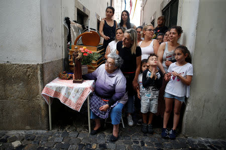 People watch the Saint Anthony figure (not seen) passing by during the Saint Anthony procession in the Alfama neighbourhood in Lisbon, Portugal, June 13, 2018. Picture taken June 13, 2018. REUTERS/Pedro Nunes