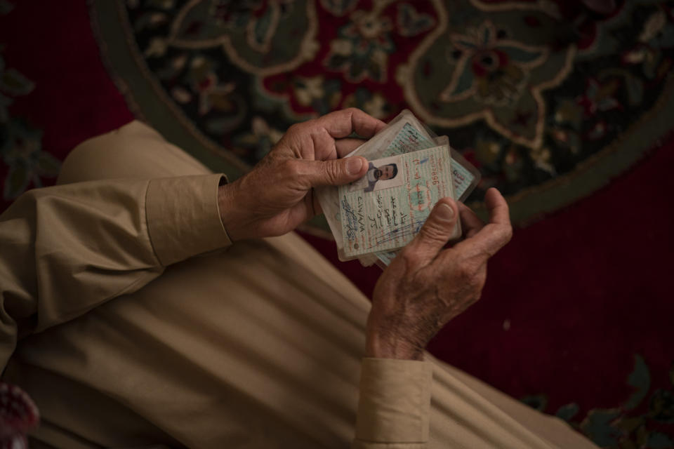 In this April 14, 2019 photo, Hussein Abd holds the ID's of his three dead sons as he sits in his house during an interview in Mosul, Iraq. They were killed in Badoush by Islamic State militants in a January attack. (AP Photo/Felipe Dana)