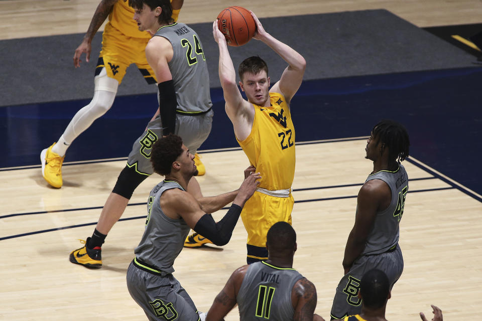 West Virginia guard Sean McNeil (22) passes while defended by Baylor guards MaCio Teague (31), Mark Vital (11) and Davion Mitchell (45) during the second half of an NCAA college basketball game Tuesday, March 2, 2021, in Morgantown, W.Va. (AP Photo/Kathleen Batten)