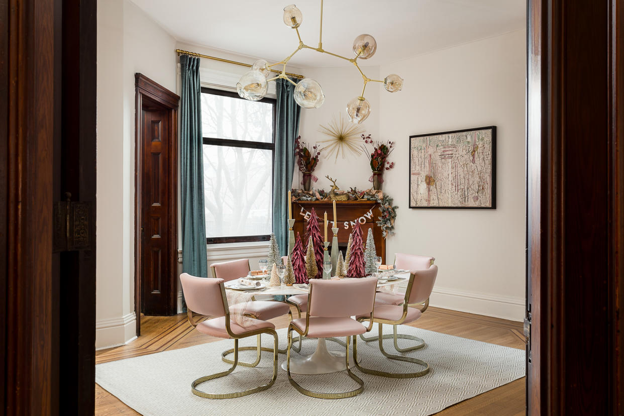  A dining room with pink chairs and plum toned trees on the table. 