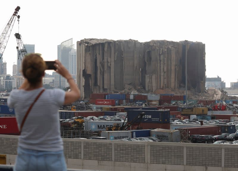 A woman uses her phone near the partially-collapsed Beirut grain silos, damaged in the August 2020 port blast, in Beirut