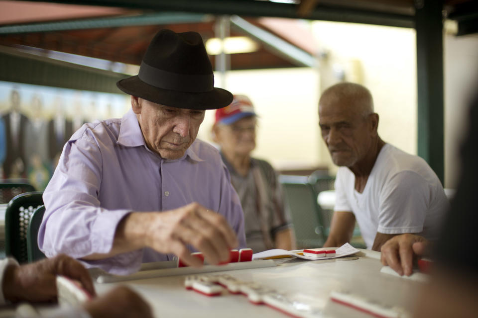 This May 2, 2014 photo shows men playing dominoes on Calle Ocho (Eighth Street) in Miami's Little Havana. Once a refuge for Cuban exiles rekindling the tastes and sounds a lost home, today Miami’s Little Havana is a mosaic of cultures and a popular tourist destination. (AP Photo/J Pat Carter)