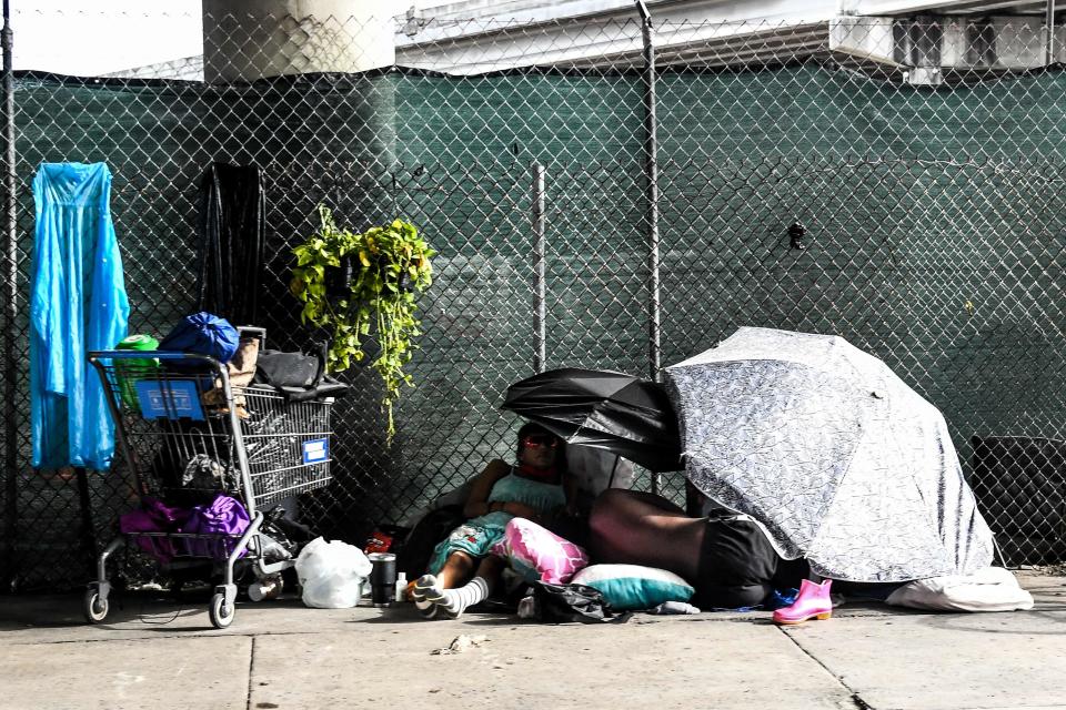 People experiencing homelessness are lying in a makeshift shelter on a sidewalk in Miami, on Aug. 4, 2021. Under Miami City Commissioner Joe Carollo's "adopt-a-homeless" plan, the city would lean on private residents to take individuals experiencing homelessness into their homes as a way to shudder encampments.