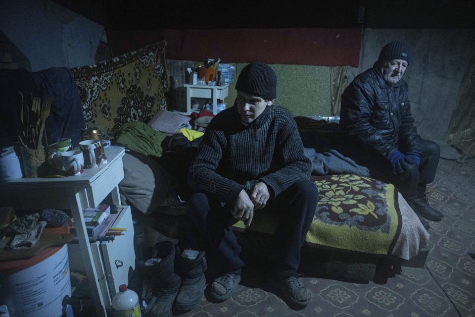Leonid sits in a basement with his neighbour as they continue to live in the city without electricity, running water and gas in Siversk, Donetsk region, Ukraine, Thursday, Jan. 12, 2023. (AP Photo/Evgeniy Maloletka)