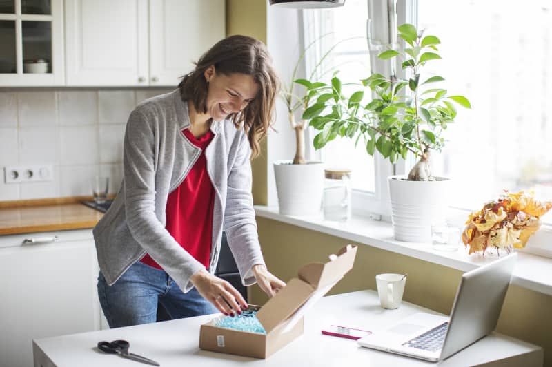 Woman opening a gift box in her kitchen