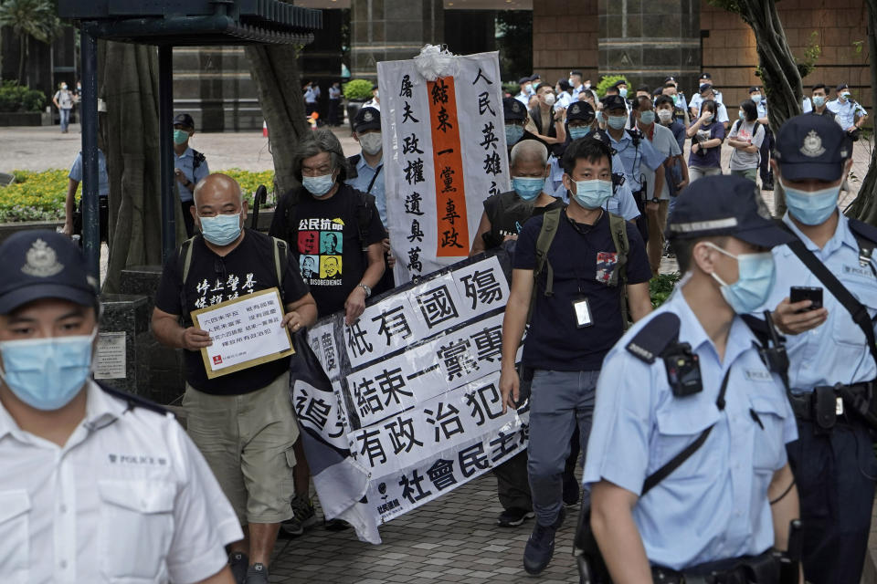 Pro-democracy activists are surrounded by police officers as they march toward a flag raising ceremony in Hong Kong, Thursday, Oct. 1, 2020 to mark the China's National Day. The banner reads " Stop One Party Ruling." (AP Photo/Kin Cheung)