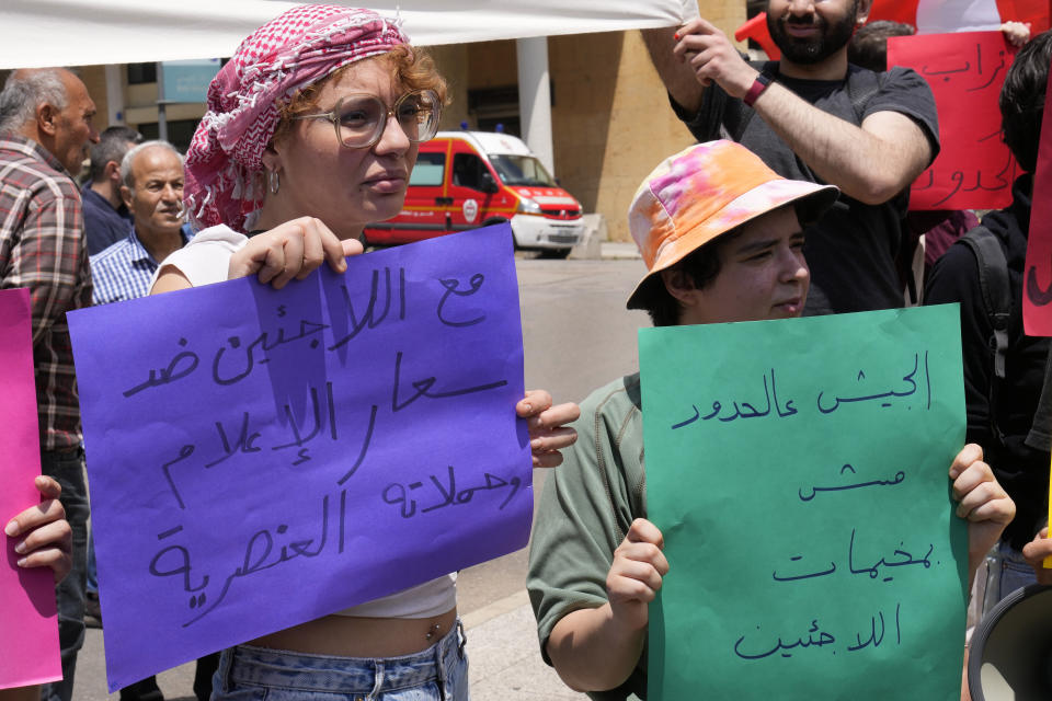 Protesters hold signs reading "With the refugees against the media frenzy and racist campaigns" and "The army's place is on the borders, not in the refugee camps" in Arabic at a workers' day march held by leftist groups in Beirut, Lebanon, Monday, May 1, 2023. The slogans came in response to increased pressure by Lebanese authorities on Syrian refugees in recent weeks, including raids, arrests and deportations. (AP Photo/Hussein Malla)