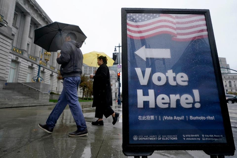 People carry umbrellas while walking past a voting sign outside City Hall in San Francisco (Copyright 2022 The Associated Press. All rights reserved)