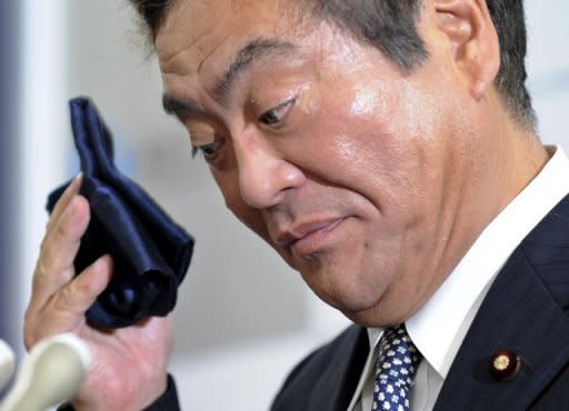 Japanese Economy, Trade and Industry Minister Yoshio Hachiro wipes his sweat with a handkerchief during a news conference in Tokyo