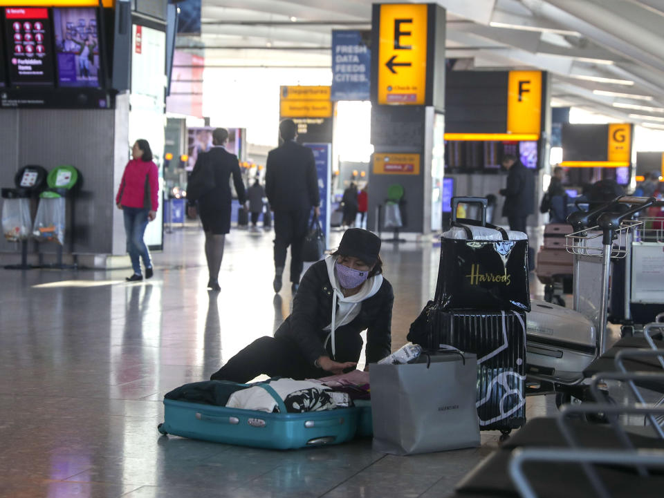 A woman wearing a face mask packs her suitcase in the departures area of Terminal 5, after it was announced British Airways has suspended all services to and from China, at London's Heathrow Airport, Wednesday, Jan. 29, 2020. British Airways and Asian budget carriers Lion Air and Seoul Air are among the airlines suspending flights to China as fears of a new virus that has killed more than 130 people spread. Several other airlines including Finnair, Hong Kong-based Cathay Pacific and Singapore-based Jetstar Asia are reducing the number of flights to the country as demand for travel drops because of the outbreak. (Steve Parsons/PA via AP)