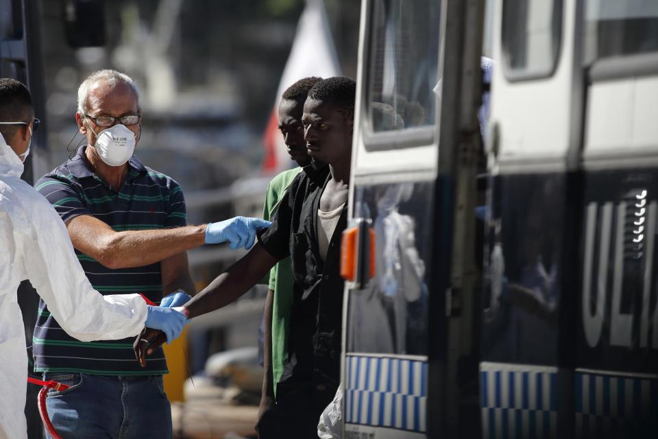 Rescued migrants are fitted with identity bracelets as they walk to a police bus at the AFM Maritime Squadron base at Haywharf in Valletta's Marsamxett Harbour