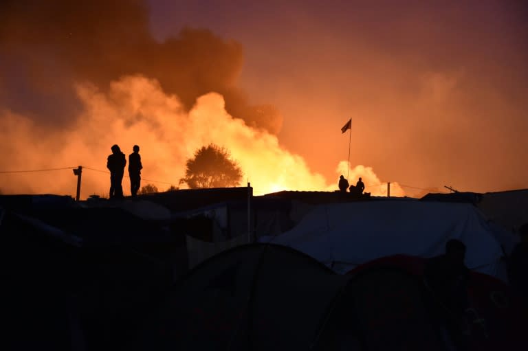 People look at smoke rising during the demolition of the Calais "Jungle" camp in northern France on October 25, 2016