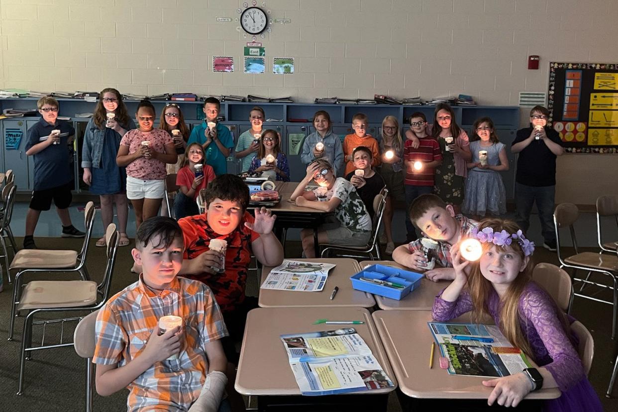 A class of fourth-grades shines their plastic bottle flashlights, which they assembled in class.