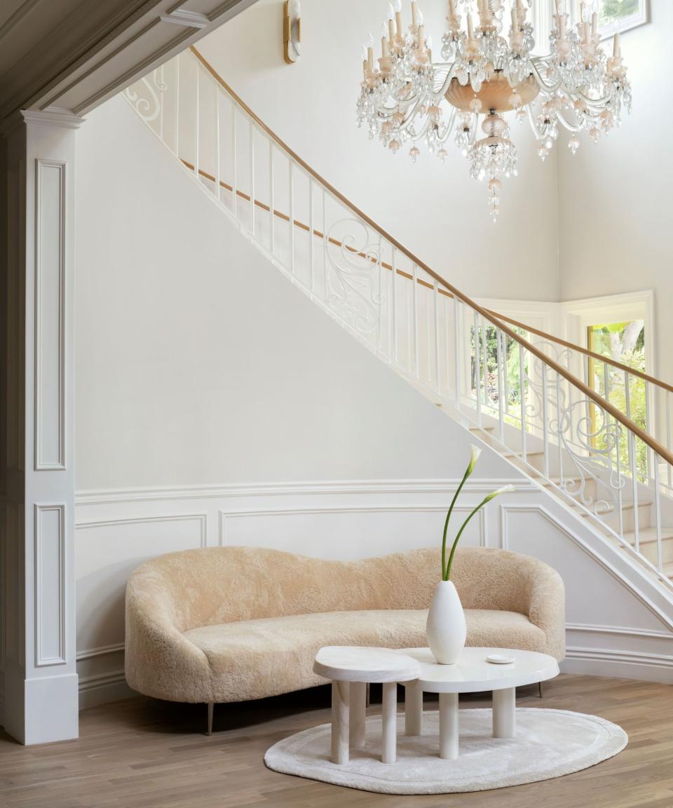 grand curved staircase with chandelier white walls and ivory curved sofa