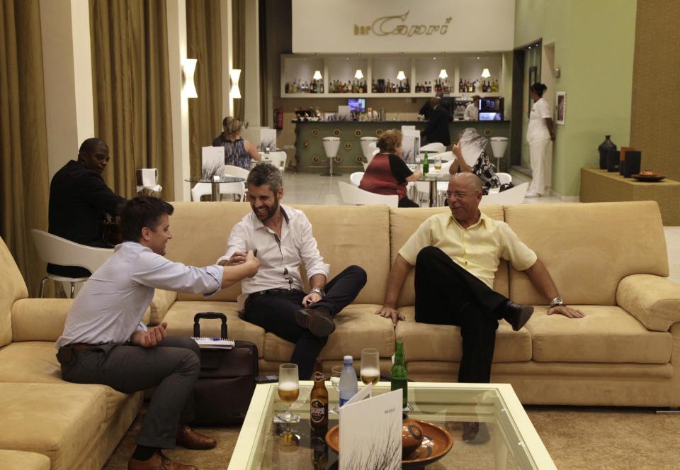 In this Feb. 7, 2014 photo, tourists joke as they look at a cell phone in the lobby of the Capri hotel in Havana, Cuba. Built in late 1957, the Capri enjoyed a brief but madcap run as one of the flashiest mob joints of the time. (AP Photo/Franklin Reyes)