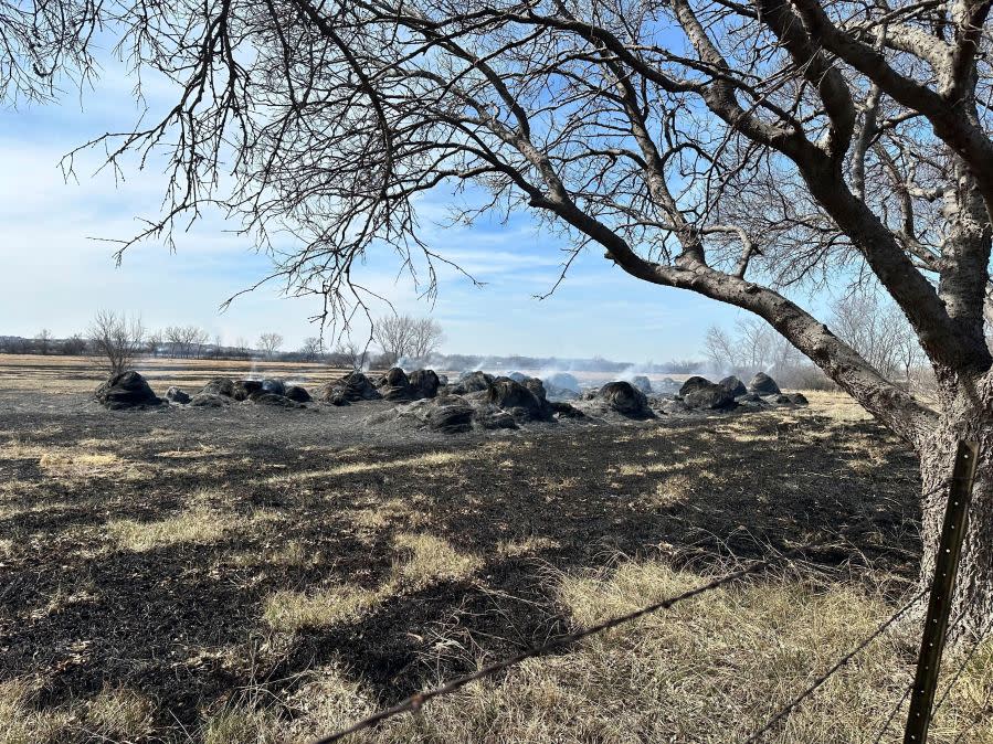 Smoke rises from smoldering hay bales outside the town of Canadian, Texas on Wednesday, Feb 28, 2024. A fast-moving wildfire burning through the Texas Panhandle grew into the second-largest blaze in state history Wednesday, forcing evacuations and triggering power outages as firefighters struggled to contain the widening flames. (AP Photo/Sean Murphy)
