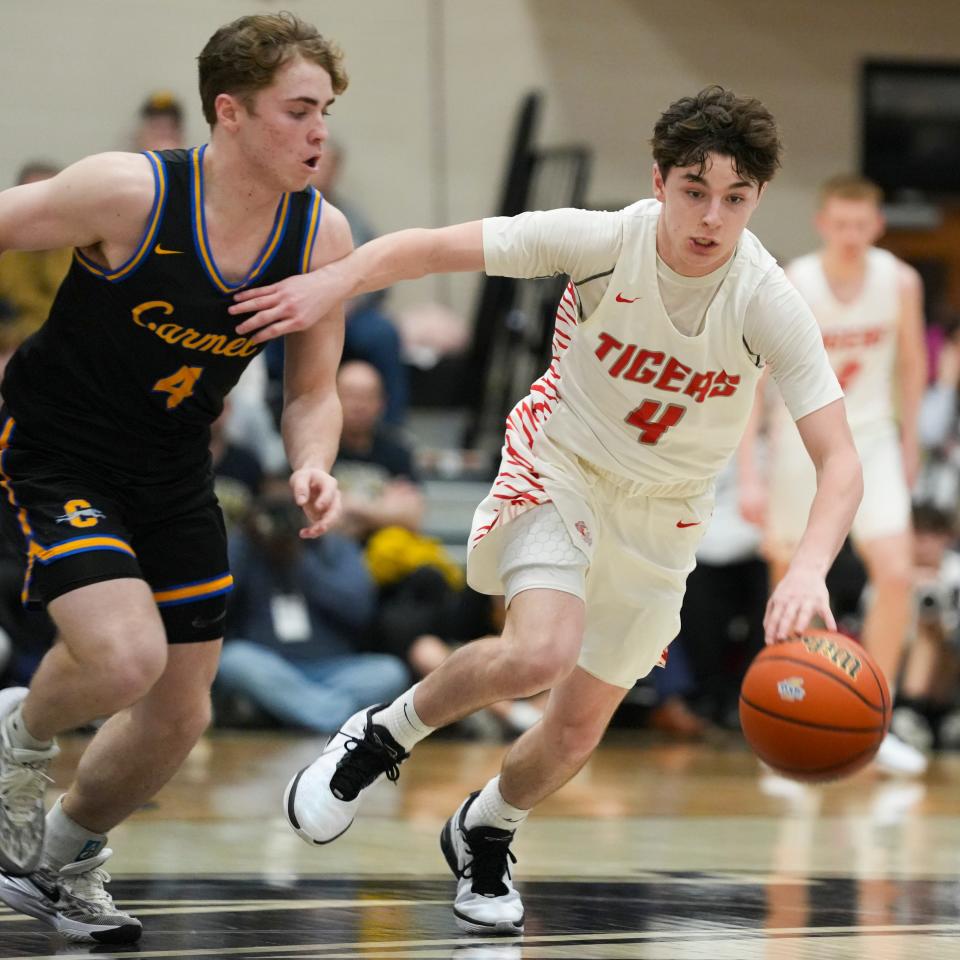 Fishers Tigers Cooper Zachary (4) dribbles the ball down the court during a fast break, Tuesday, Feb. 27, 2024, during the Class 4A sectional game at Noblesville High School in Noblesville, Indiana. Fishers beat Carmel 54-41 and advances to play the Hamilton Southeastern Royals in the Class 4A semifinals game on March 1.