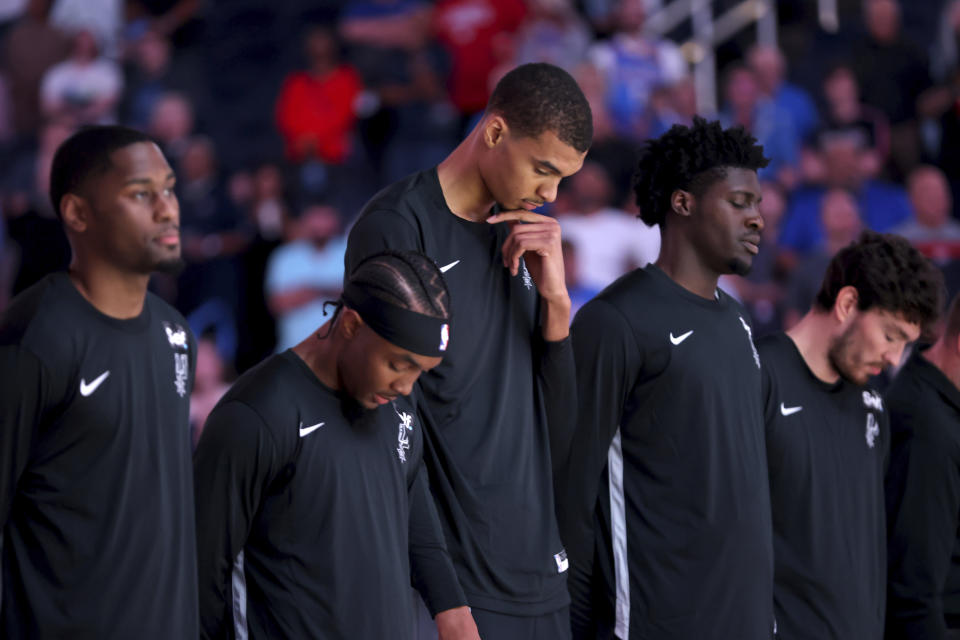 San Antonio Spurs center Victor Wembanyama, center, stands for the opening prayer before a preseason NBA basketball game against the Oklahoma City Thunder, Monday, Oct. 9, 2023, in Oklahoma City. (AP Photo/Sarah Phipps)