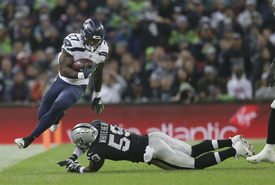 Seattle Seahawks running back Mike Davis (27), left, escapes the clutches of Oakland Raiders linebacker Tahir Whitehead (59) during the first half of an NFL football game at Wembley stadium in London, Sunday, Oct. 14, 2018. (AP Photo/Tim Ireland)