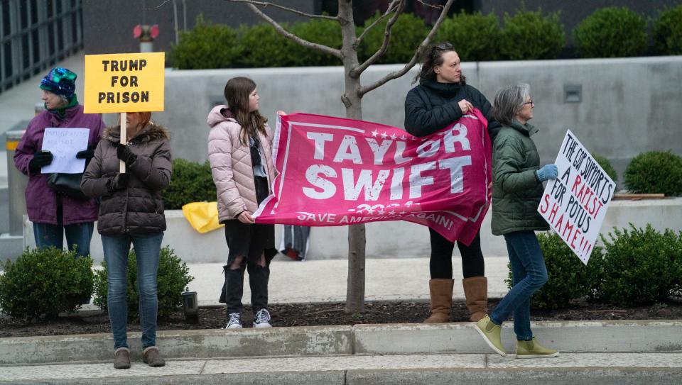 Protesters stand across the street from the DeVos Place before Donald Trump speaks at a press conference in the Monroe Meeting Rooms at DeVos Place in Grand Rapids on Tuesday, April 2, 2024.