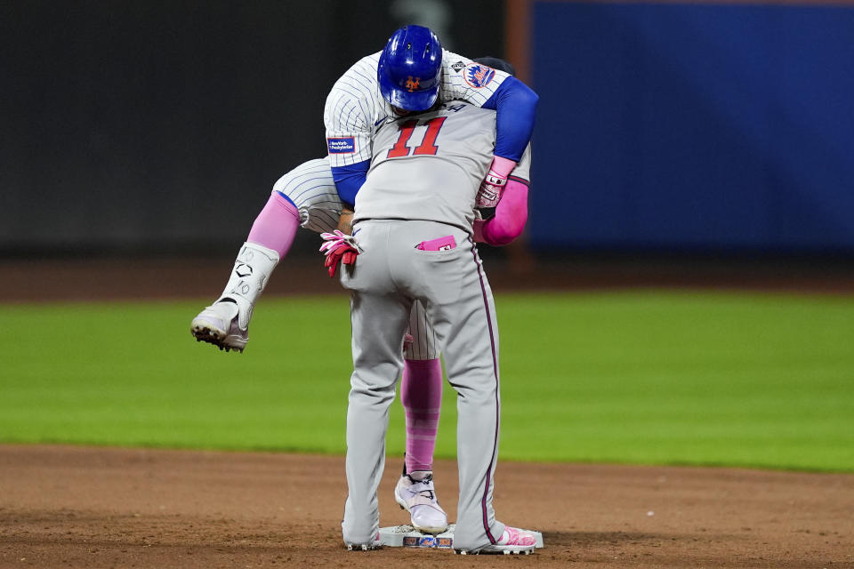 New York Mets' Francisco Lindor, top, climbs on Atlanta Braves shortstop Orlando Arcia (11) after doubling on a sharp line drive during the sixth inning of a baseball game, Sunday, May 12, 2024, in New York. (AP Photo/Julia Nikhinson)