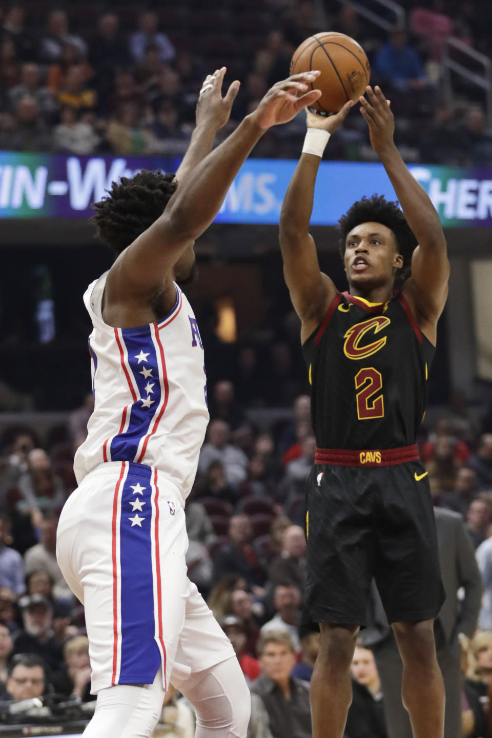 Cleveland Cavaliers' Collin Sexton, right, shoots over Philadelphia 76ers' Joel Embiid in the first half of an NBA basketball game, Wednesday, Feb. 26, 2020, in Cleveland. (AP Photo/Tony Dejak)